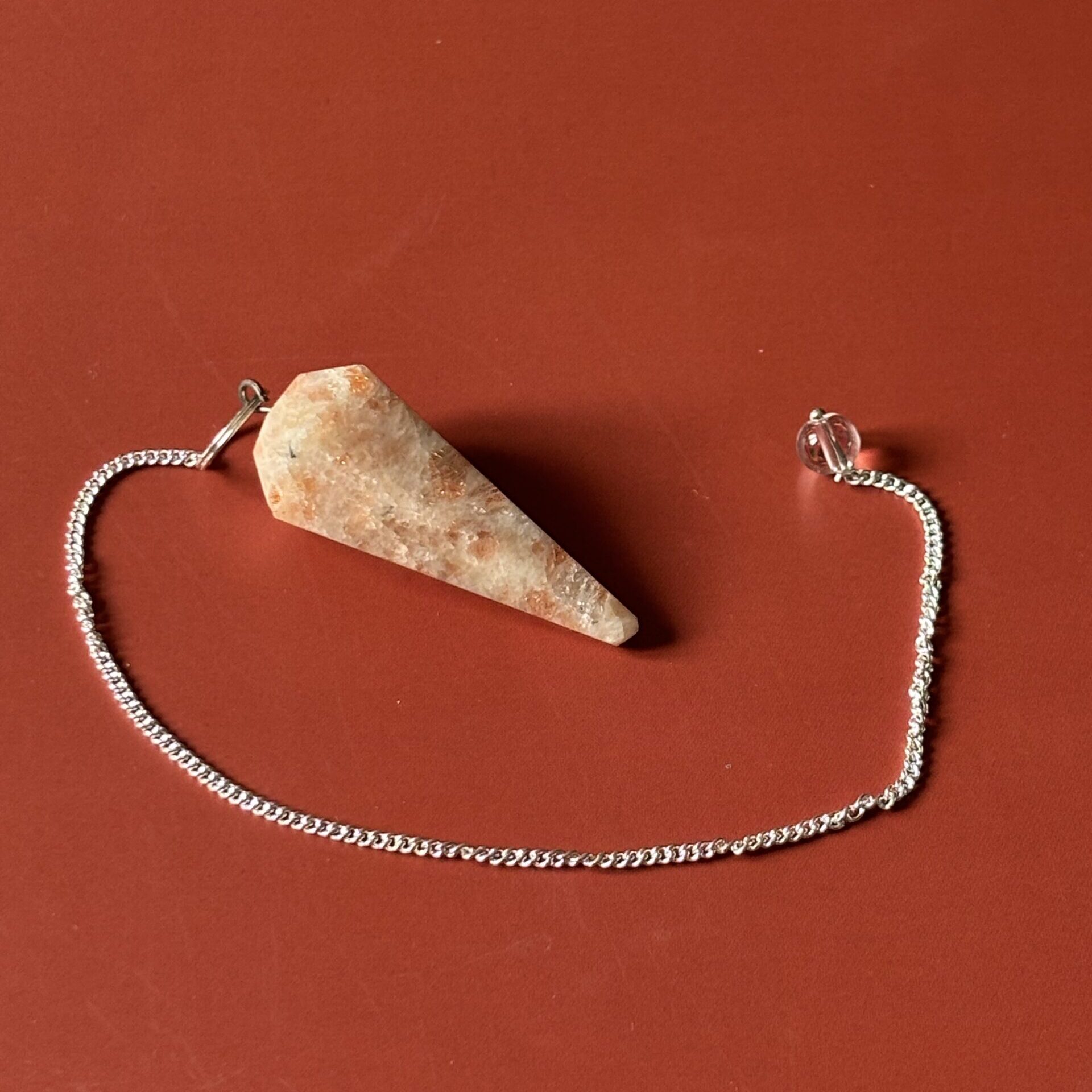 Pendule spirituel en pierre de soleil facettée, idéal pour la méditation et le bien-être